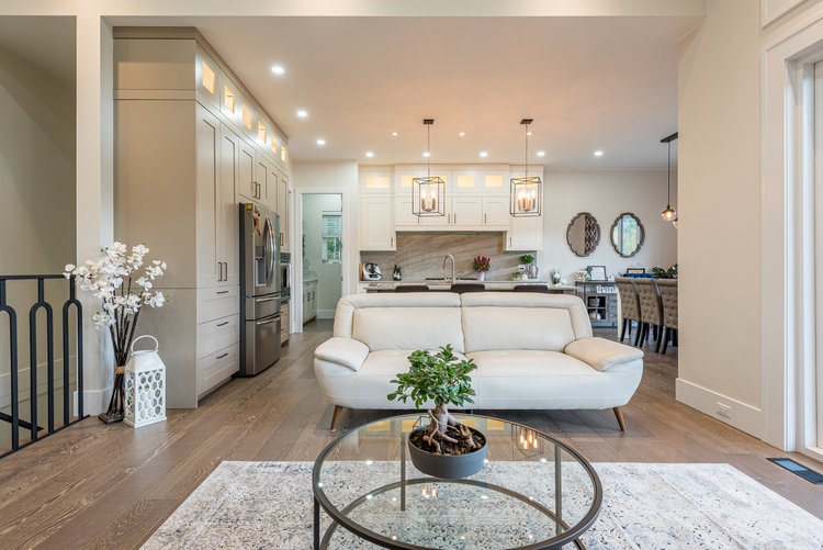 Open-concept living room and kitchen with modern lighting and white cabinetry.