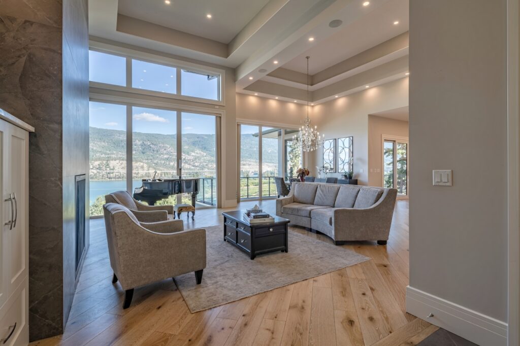 Elegant living room with large windows, tray ceiling, chandelier, and panoramic mountain views.