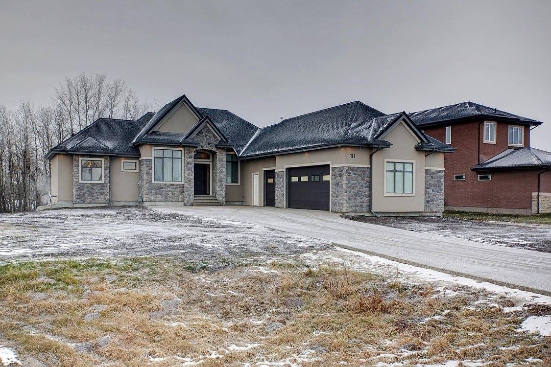 Exterior view of a large stone and stucco house with a frosty lawn and overcast sky.