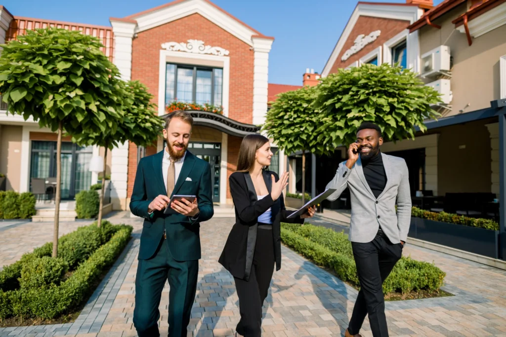 Real estate agents walking and discussing outside upscale townhomes.